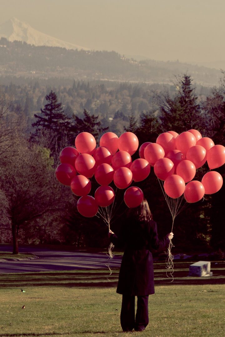 A woman holding red balloons in both her hands