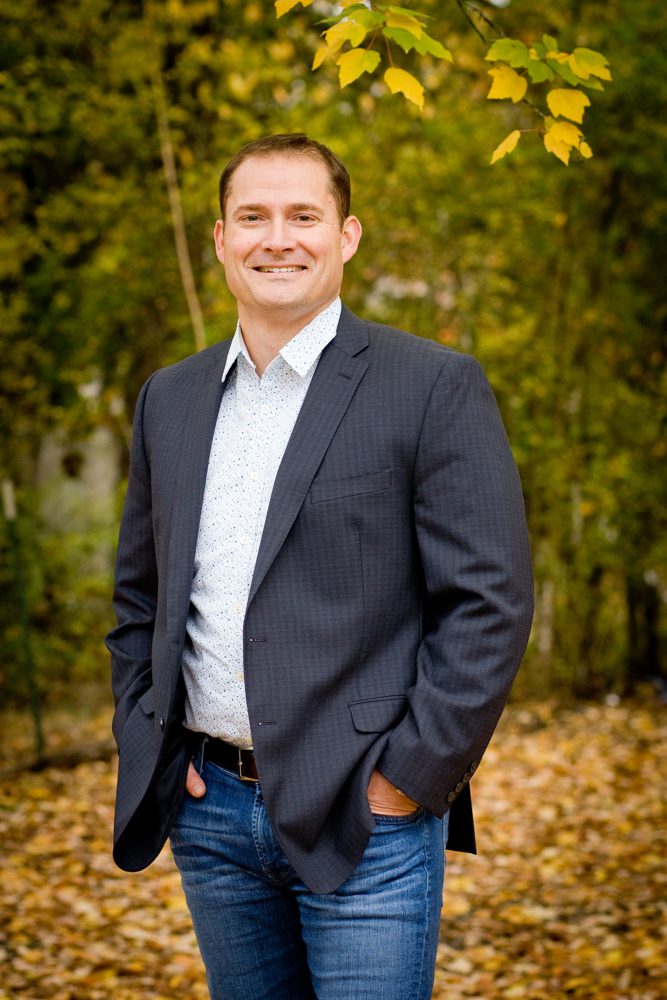 A man wearing blue suit with trees in the background