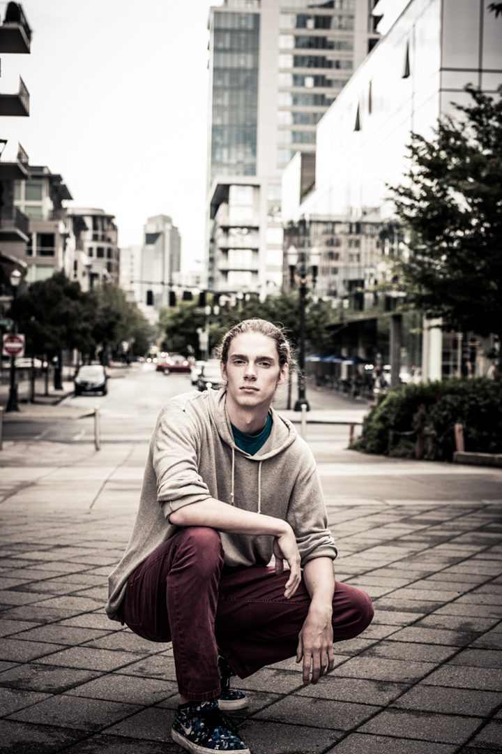 A man sitting on the ground in front of some buildings