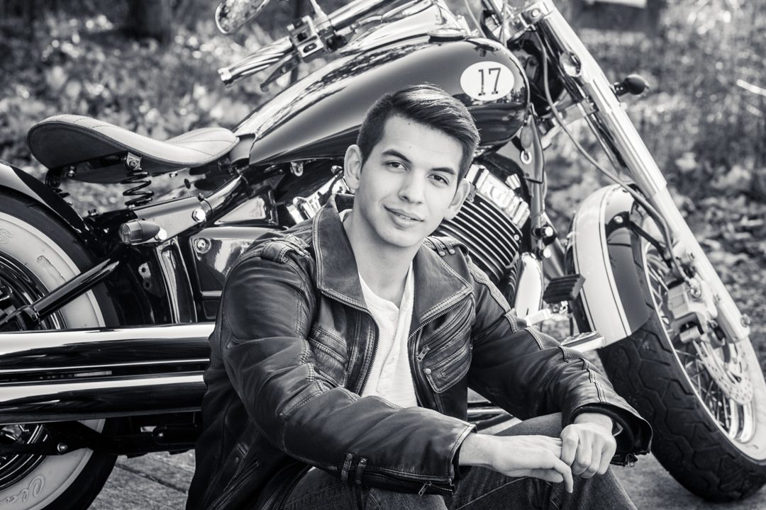 A man sitting in front of a motorcycle.