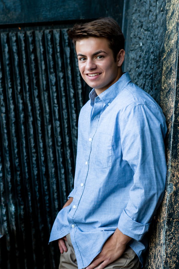 A man in blue shirt leaning against wall.