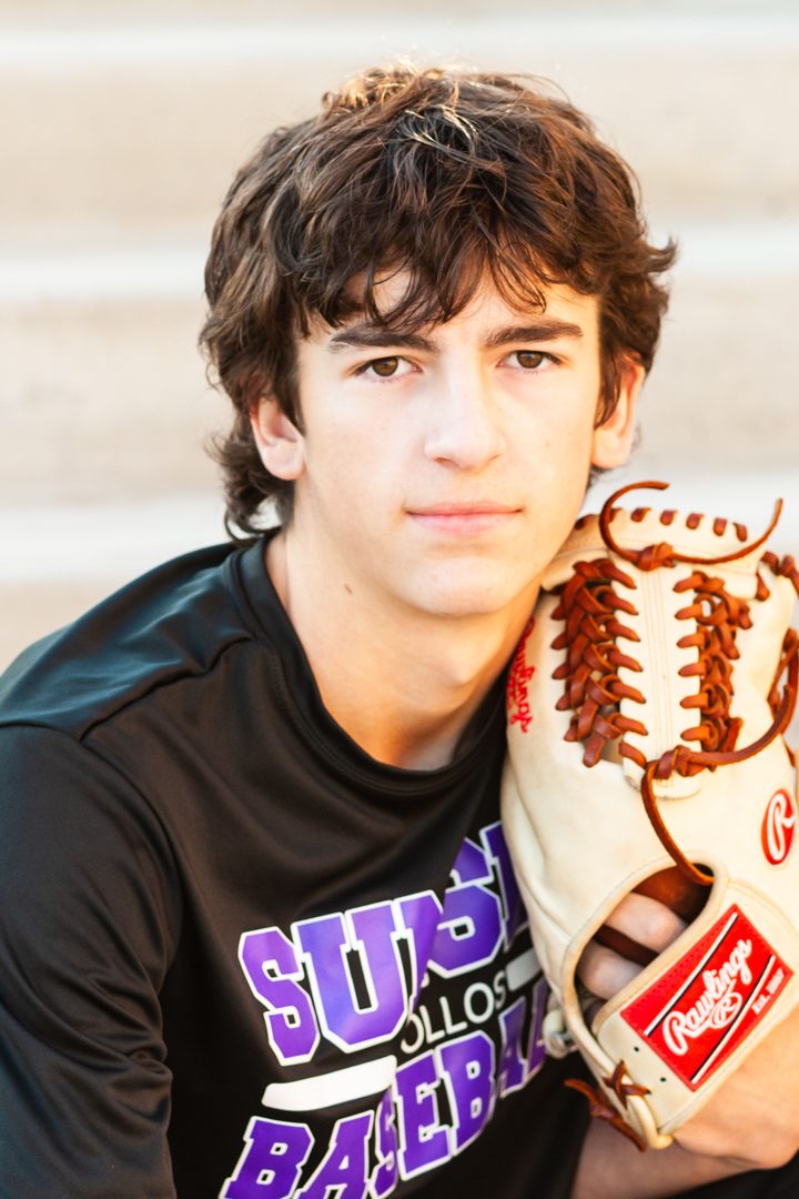 A young man with a baseball glove on his arm.