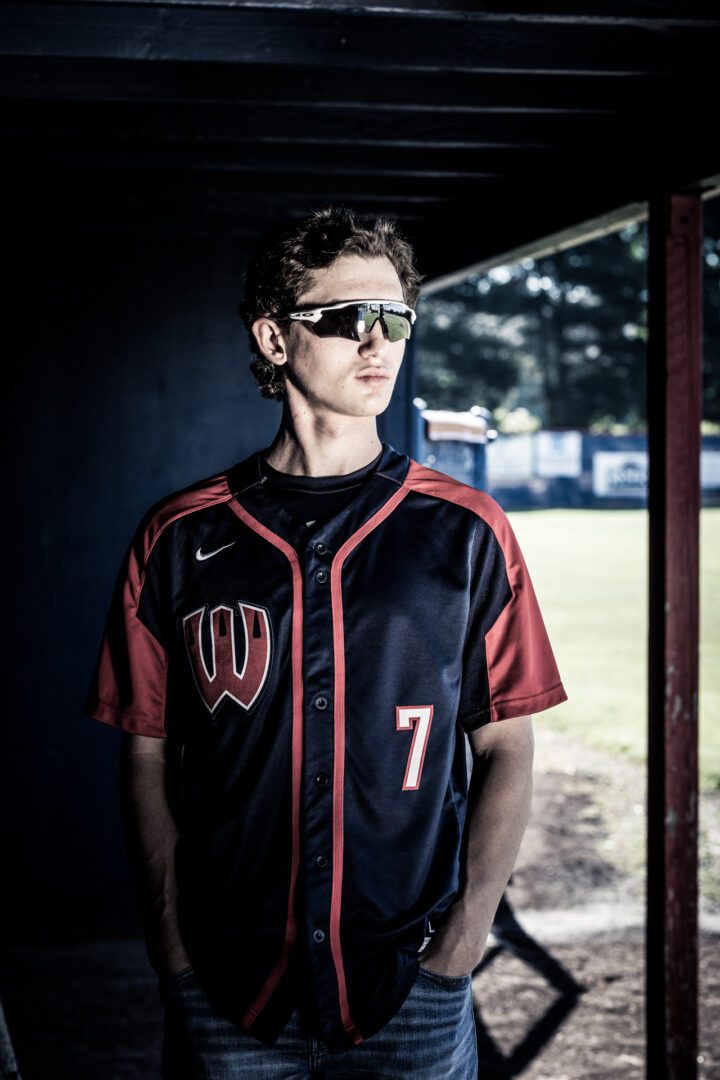 A man in sunglasses and a baseball uniform.