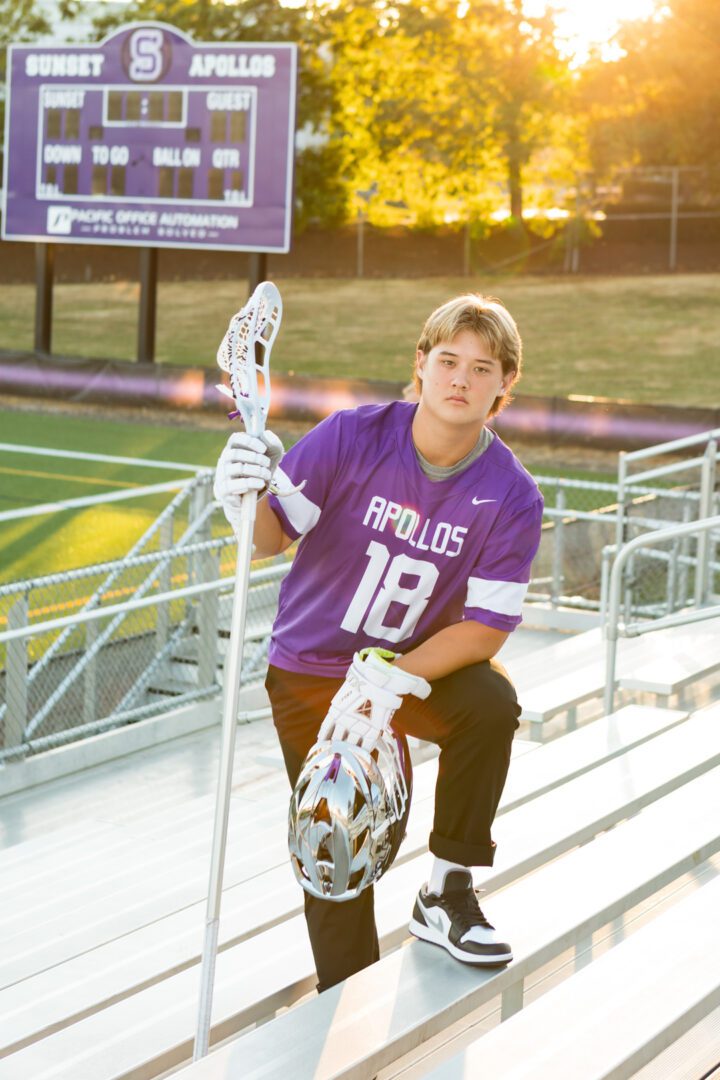 A boy in purple shirt holding a lacrosse stick.