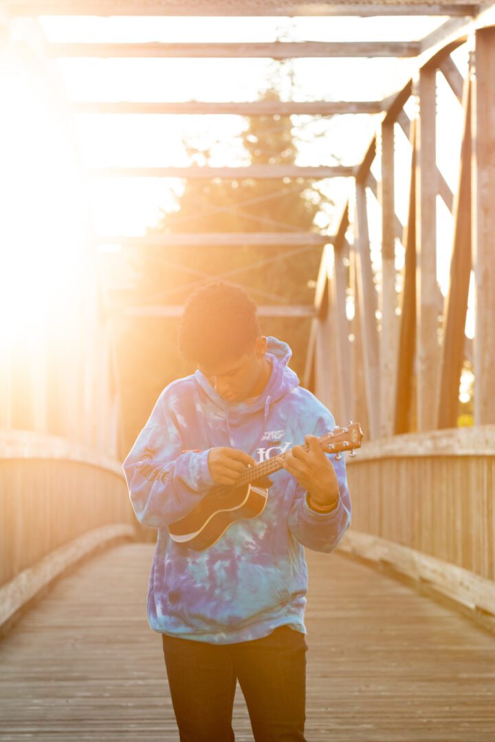 A man playing an instrument while standing on a bridge.
