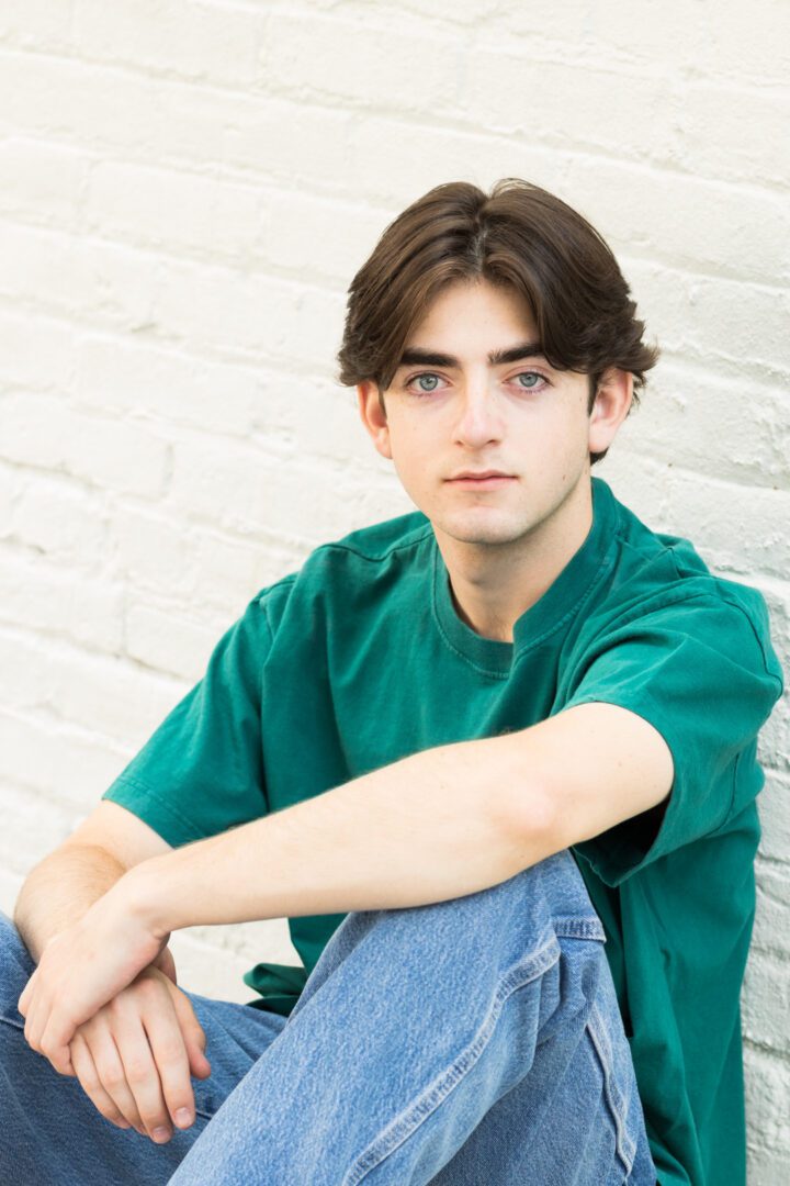 A man sitting on the ground wearing green shirt