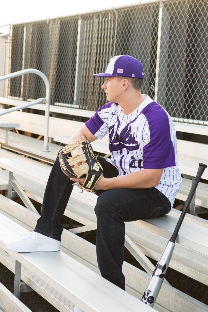 A baseball player sitting on the bench with his glove.