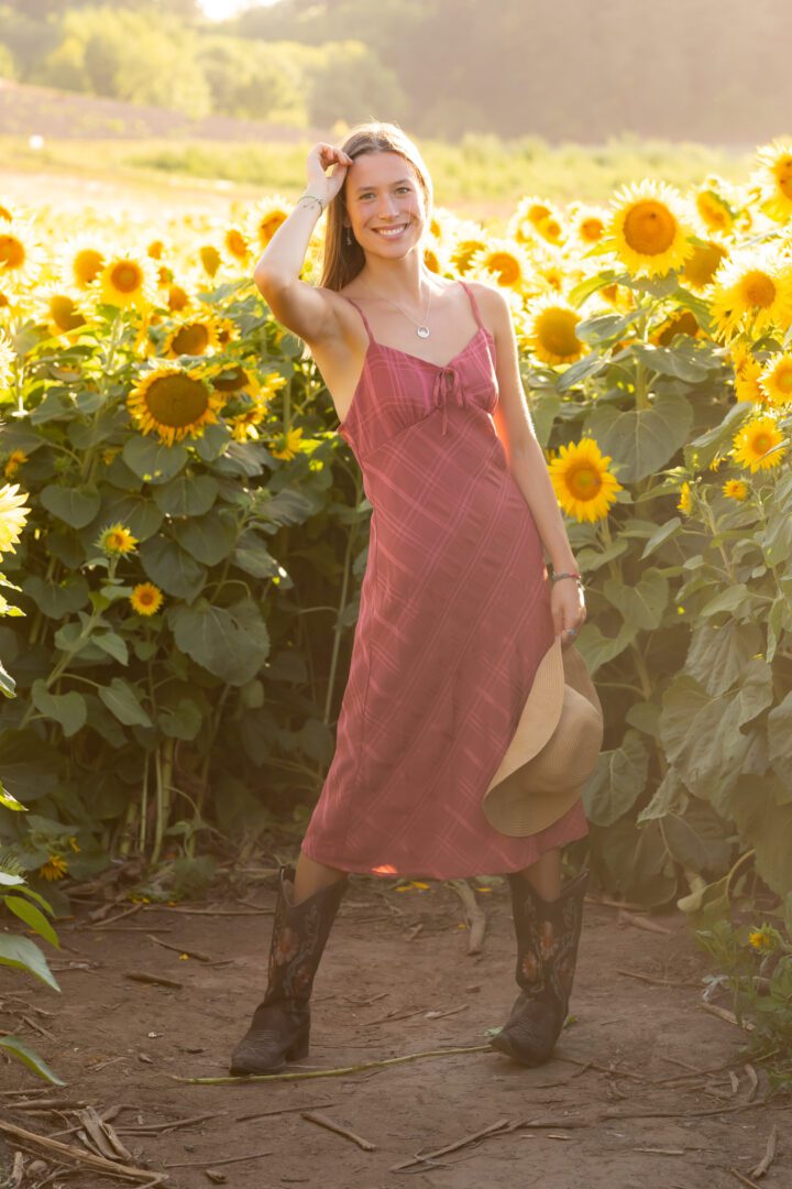 A woman in a pink dress standing next to sunflowers.