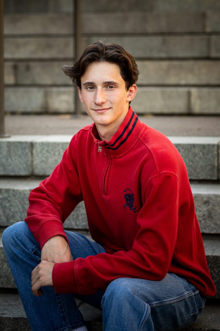 A man sitting on steps wearing a red shirt.