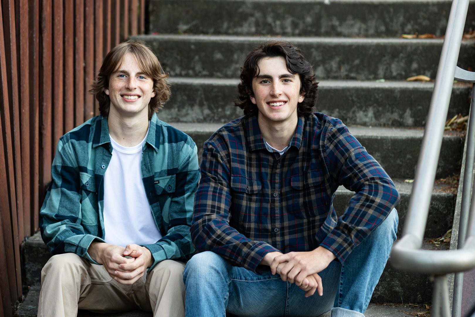 Two young men sitting on steps smiling for the camera.