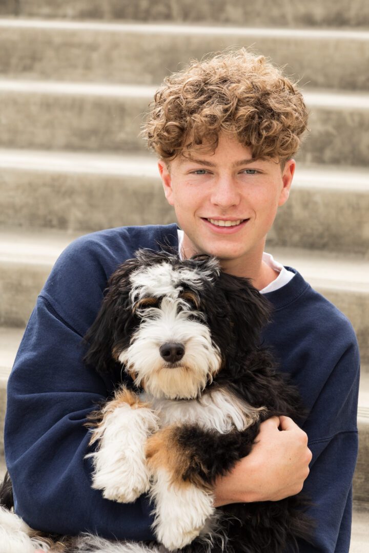 A boy holding his dog on the stairs
