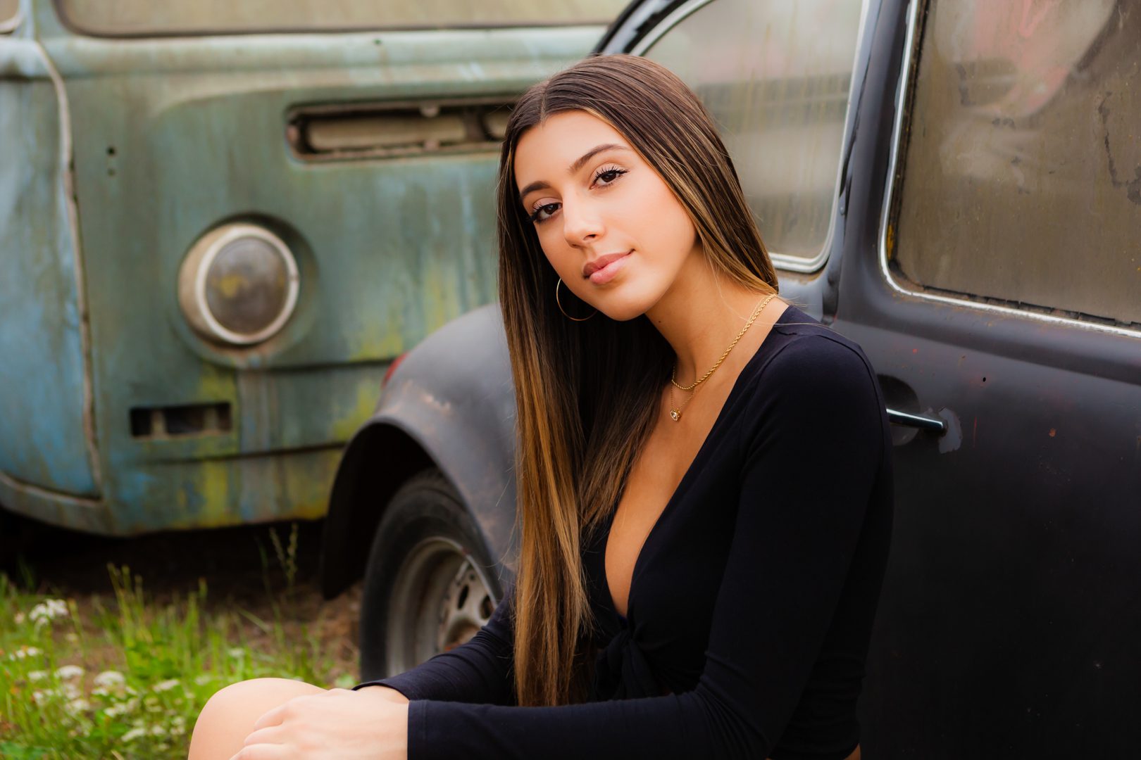 A woman sitting in front of an old car.