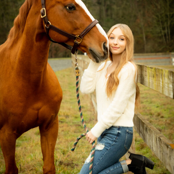 A woman standing next to a horse in the grass.